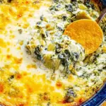 Hot spinach artichoke dip served in a bowl with tortilla chips